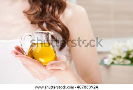 Unrecognizable woman holding glass jug with virgin olive oil - skincare and haircare concept