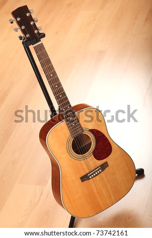 Brown guitar on black stand; neutral background