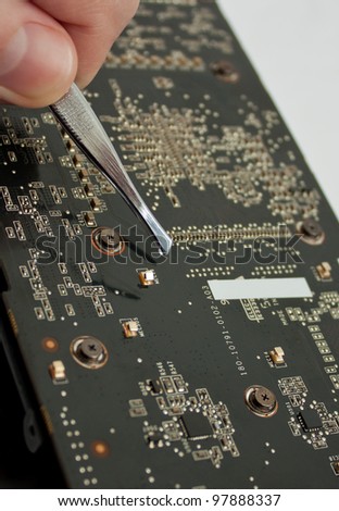 Process of repairing computer electronic board; closeup of video card and tweezers