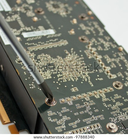 Process of repairing computer electronic board; closeup of video card and screwdriver
