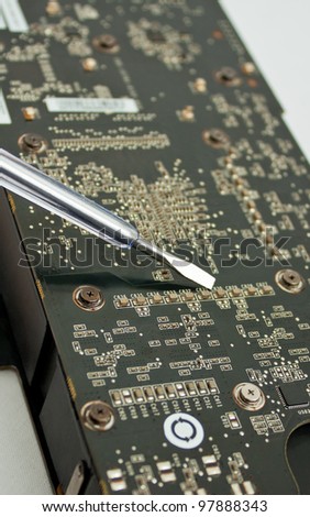 Process of repairing computer electronic board; closeup of video card and screwdriver