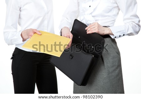 Business people exchanging documents; closeup of businesswomen\'s hands holding envelope/document/file; isolated on white background