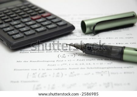 Calculator and open pen on scientific paper, shallow dof with focus on the tip of the pen