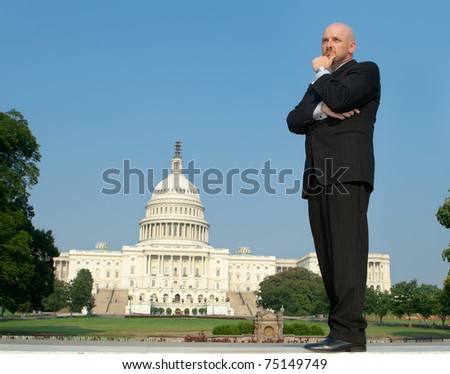 Power broker type in a suit, hand on chin standing in front of the U.S. Captiol building, downtown Washington, DC, USA.