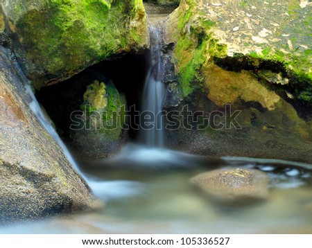 Creek and small waterfall among stones. Natural composition