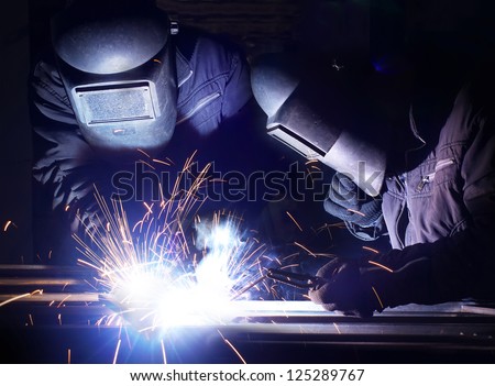 Welders team and bright sparks. Construction and manufacturing