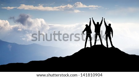Silhouettes of a team on the mountain peak. Sport and active life