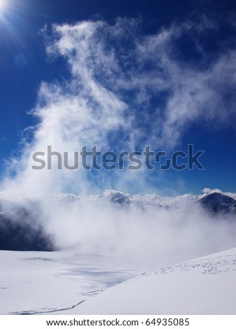 Cloud on background of the snow mountains. Natural composition