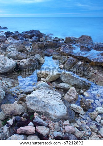 Twilight on seashores. The Stone and water with reflections.