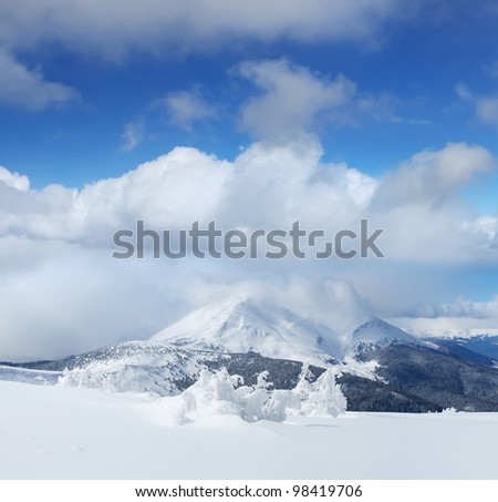 High snow summit and large clouds. Winter composition