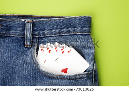 Playing cards in blue jeans pocket with green background