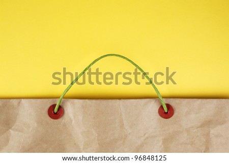 Paper bag with handles on yellow background