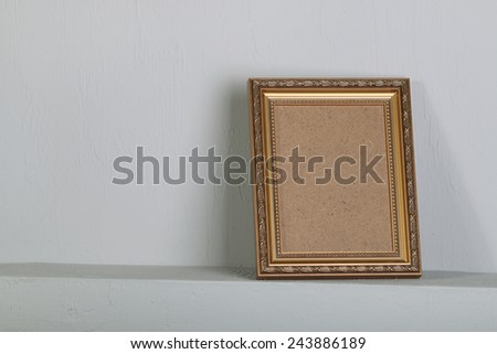 golden photo frame with space on the shelf in the background of a gray wall