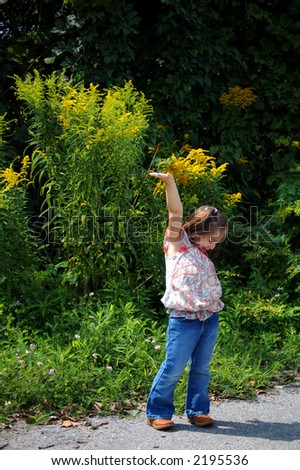 Four year old girl standing on a rural road with her hand up.  She could be holding something (your sign maybe?)