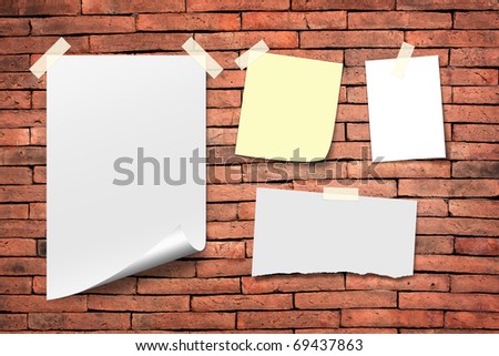 Poster paper and white paper notes. Stick tape on the orange brick wall.
