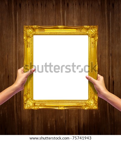 Gold frame in woman hand isolated on old wood background.