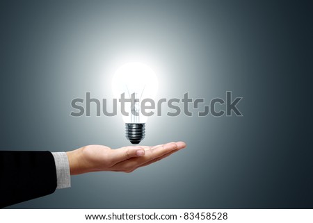 Light bulb in hand business woman on gray background