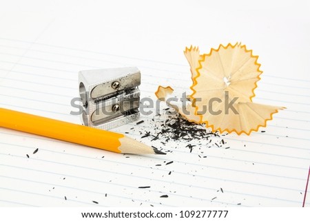 Sharpened pencil next to the sharpener and shavings.
