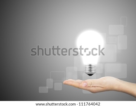Light bulb in hand on gray background