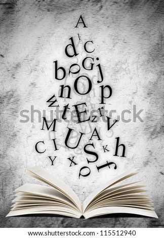 Open book with falling letters over grunge abstract background