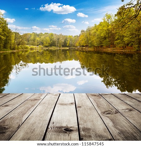 Beautiful autumn forest with reflection in the water and wood planks. Beauty nature background