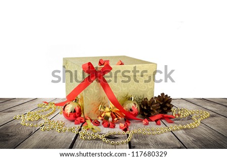 Golden christmas gift box with christmas balls over wooden planks and white background