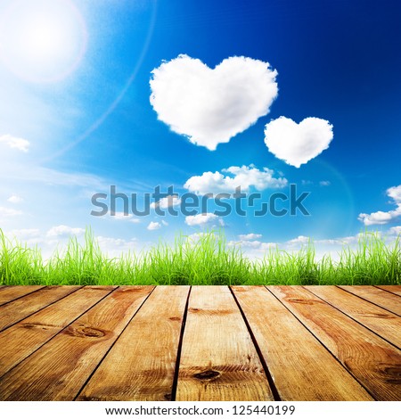 Green grass on wooden plank over a blue sky with hearts shape clouds Beauty natural background Green grass on wooden plank over a blue sky with hearts shape clouds Beauty natural background