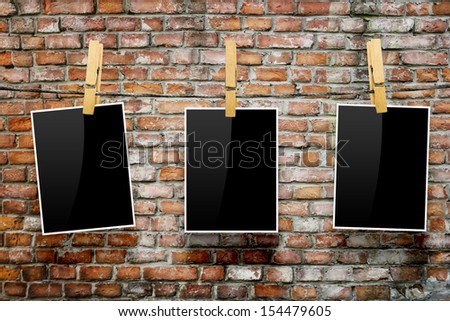 Photo frames with pins on rope over old aged brick wall background