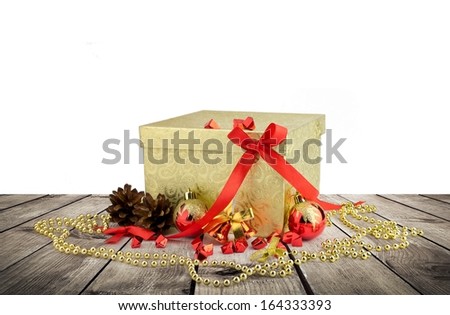 Golden christmas gift box with christmas balls over wooden planks and white background