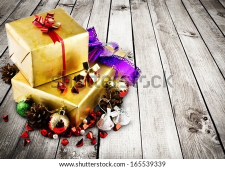 Golden christmas gift box with christmas balls over wood background