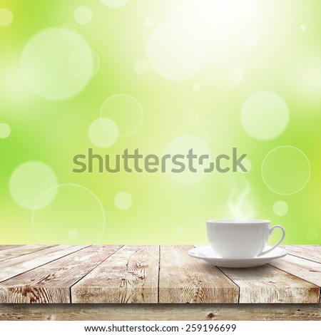 Cup with hot drink on table over Green bokeh and sunlight. Beauty morning breakfast background