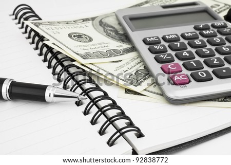 Pen,calculator and dollars on notebook closeup. Business concept