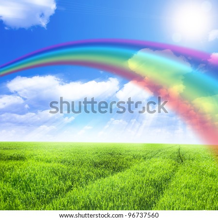 Green field under blue sky with sun and rainbow