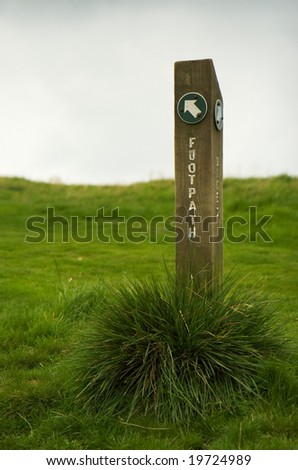 A footpath sign with grass growing around the base. Peak District. September 2008