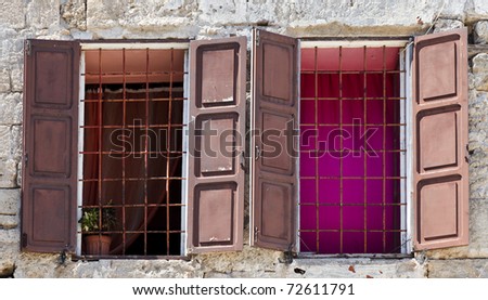 Two barred windows with open wooden shutters