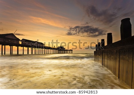 Southwold pier in Suffolk at dawn. The water reflecting off the side of the wooden groyne.