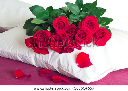 red roses on a white pillow on red sheets