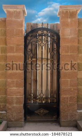 wrought-iron gates in an stone fence on sky background