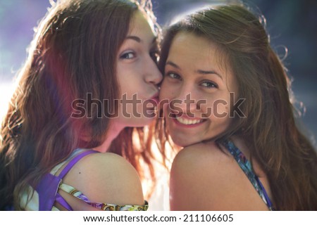 girl kissing his girlfriend and looking at the camera