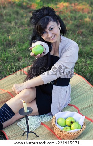 girl sitting on a rug gives a green apple