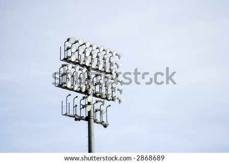 Stadium lights and speakers on a tall steel tower