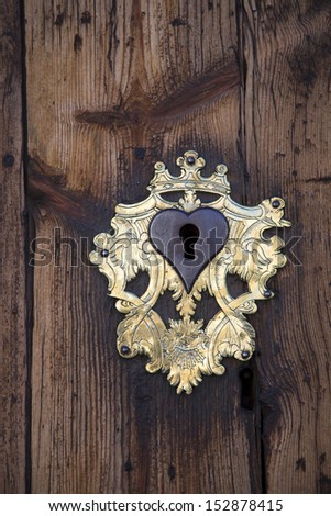 Keyhole with brass plate in heart shape on an old wooden door