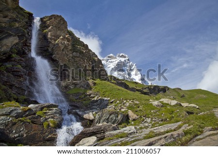 Waterfall with the snowy peaks of the south face of the Matterhorn in Breuil Cervinia Italy