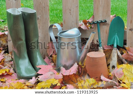 garden accessories on dead leaves in front of a wooden fence in the garden