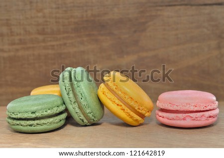 macaroons pink, green and yellow arranged on a wooden background