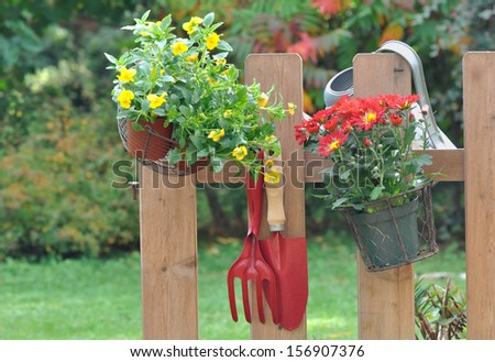 Gardening tools and flower pot hanging on a fence