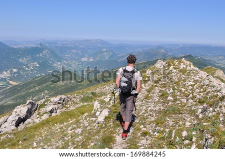 hiker walking alone on a trail at the top of the mountains