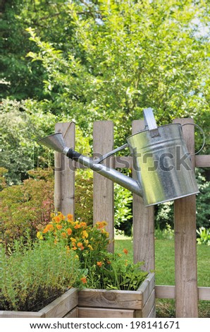 watering can hanging on a wooden fence in a garden