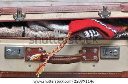 small suitcase filled ajar and warm clothing