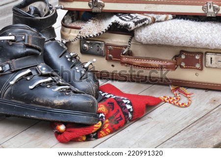 small open suitcase full of warm clothes with old ski boots